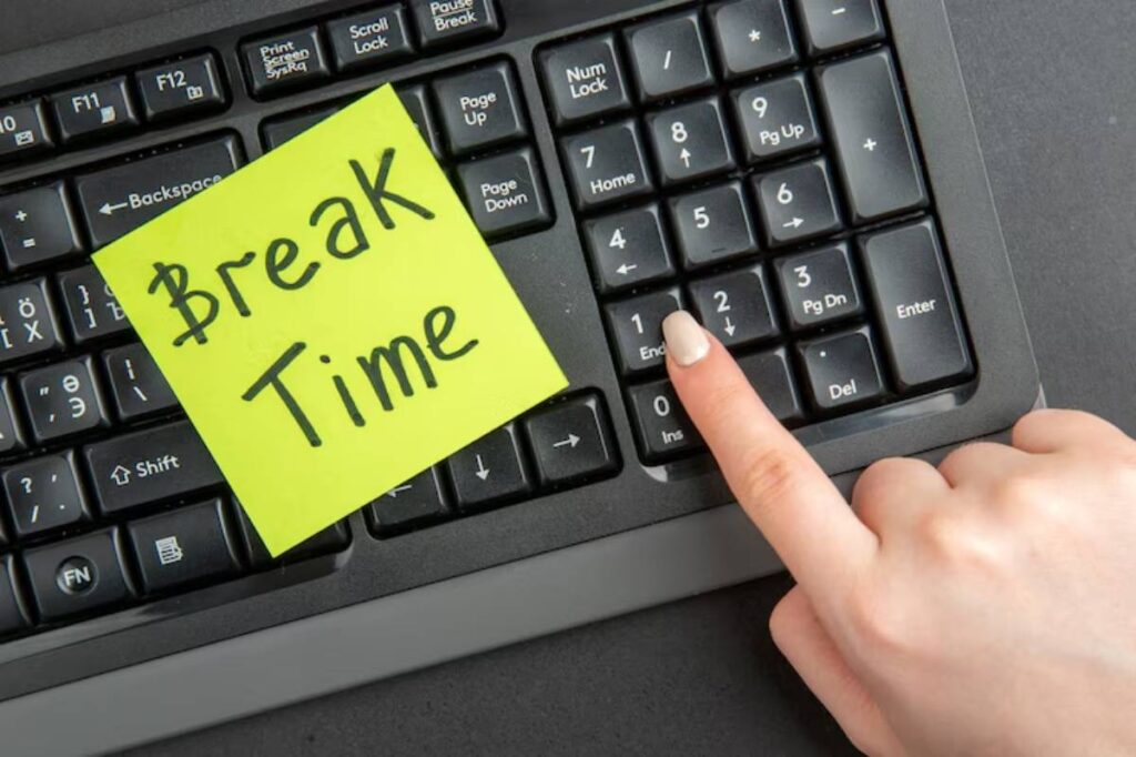 A hand pressing the "End" key on a keyboard with a yellow sticky note reading "Break Time" prominently displayed.