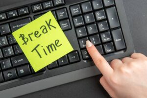 A hand pressing the "End" key on a keyboard with a yellow sticky note reading "Break Time" prominently displayed.