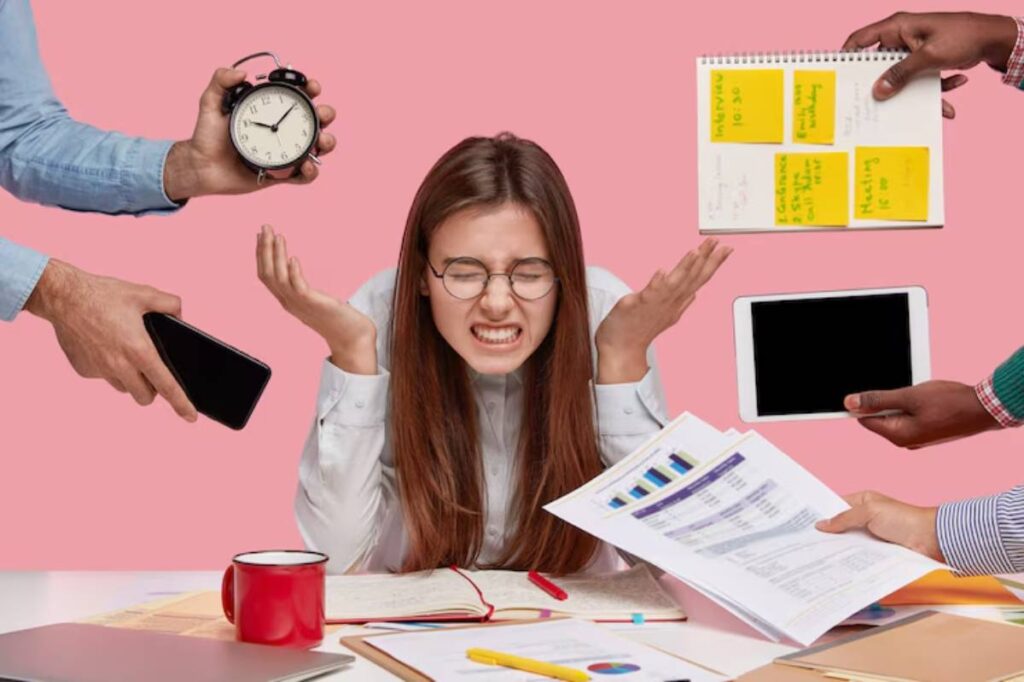 A stressed individual with outstretched hands surrounded by a clock, phone, tablet, and paperwork, set against a pink background.